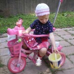 На розовом велосипеде с ведром.