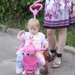 Розовый жираф на велосипеде.